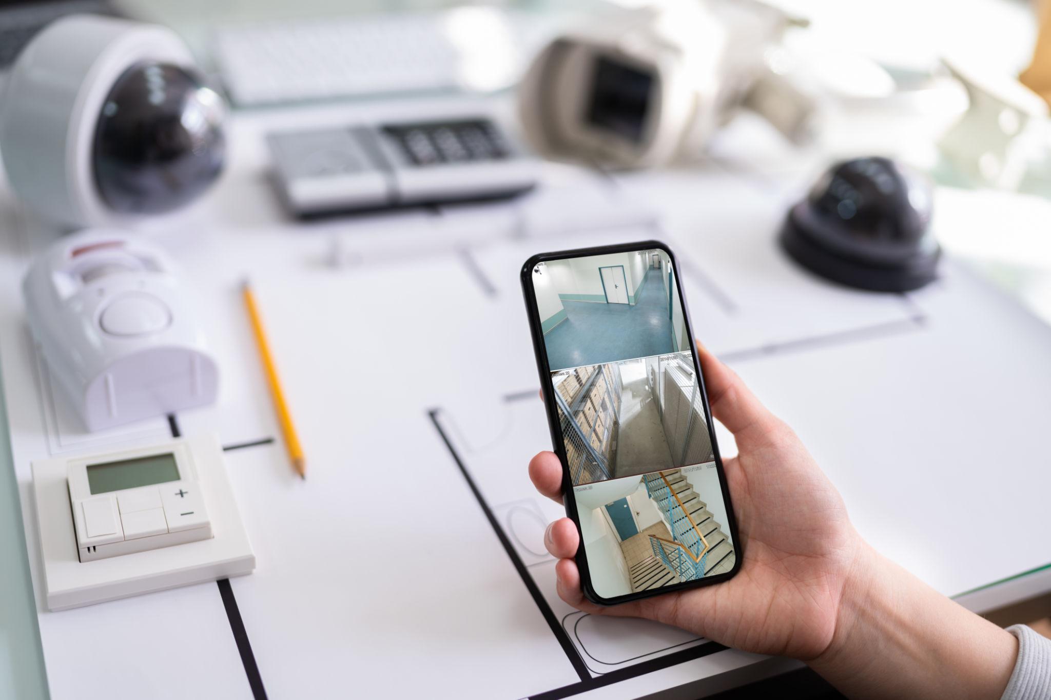 Mobile app showing live security camera feeds over system plans